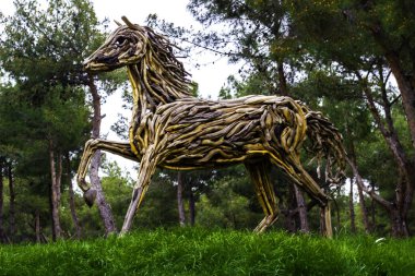 Ağaçların ve çimenlerin arasında ağaçtan yapılmış güzel tahta at.