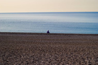 Yalnız adam Antalya 'da, Konyaalti sahilinde oturur ve denizi izler..
