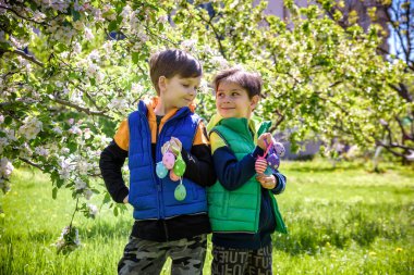 Başarılı yumurta avından sonra iki kardeş arkadaş ellerinde paskalya yumurtalarıyla ayakta ve gülümsüyorlar. Geleneksel Paskalya avı.