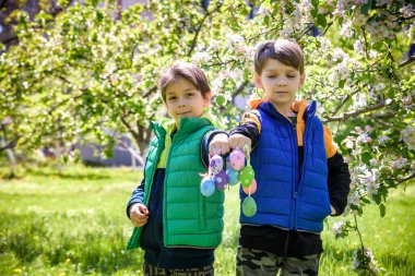 Başarılı yumurta avından sonra iki kardeş arkadaş ellerinde paskalya yumurtalarıyla ayakta ve gülümsüyorlar. Geleneksel Paskalya avı.
