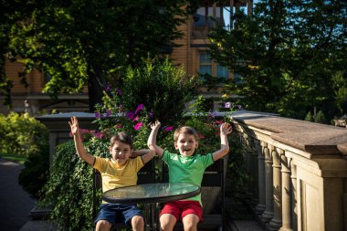 İki küçük çocuk otel restoranında ya da şehir kafesinde sağlıklı bir kahvaltı için masada bekliyor. Çocuk rahat sandalyeye oturur, rahatlar, tatilinin tadını çıkarır. Çocuk konseptiyle yaz tatili.