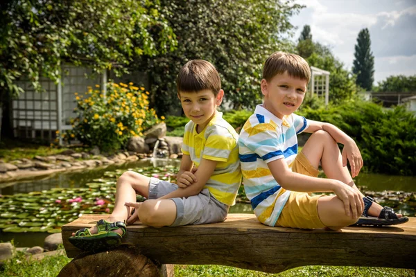 Dwóch Braci Chłopców Siedzących Ławce Parku Pobliżu Spokojnego Jeziora Lilią — Zdjęcie stockowe