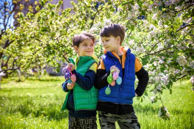 Başarılı yumurta avından sonra iki kardeş arkadaş ellerinde paskalya yumurtalarıyla ayakta ve gülümsüyorlar. Geleneksel Paskalya avı.