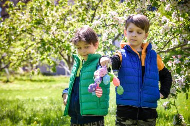 Başarılı yumurta avından sonra iki kardeş arkadaş ellerinde paskalya yumurtalarıyla ayakta ve gülümsüyorlar. Geleneksel Paskalya avı.