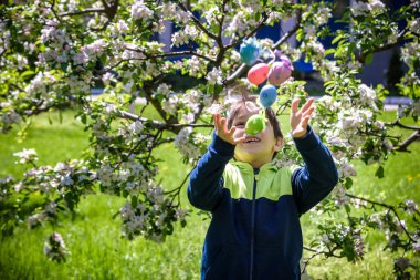 Paskalya yumurtalarını yumurta avından sonra kusan çocuk. Geleneksel Paskalya konsepti. Mutlu çocuk yeşil alan arka planında gülümsüyor.