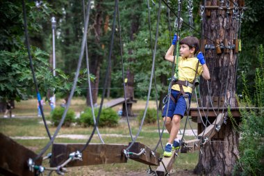 Halat parkında oynayan heyecanlı genç çocuk. Güneşli bir günde günlük giysiler ve spor ayakkabılar giyen beyaz bir çocuk. Çocuk konseptiyle aktif boş zaman.