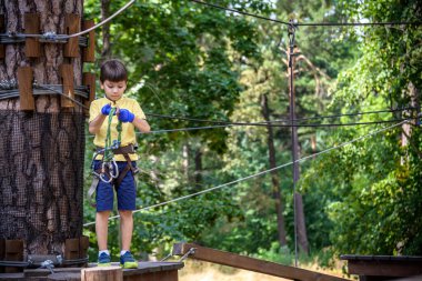 Halat parkında oynayan heyecanlı genç çocuk. Güneşli bir günde günlük giysiler ve spor ayakkabılar giyen beyaz bir çocuk. Çocuk konseptiyle aktif boş zaman.