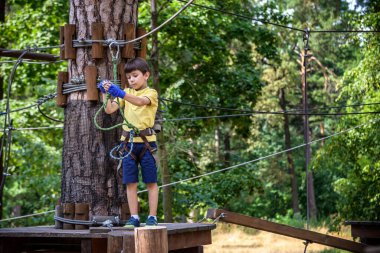 Halat parkında oynayan heyecanlı genç çocuk. Güneşli bir günde günlük giysiler ve spor ayakkabılar giyen beyaz bir çocuk. Çocuk konseptiyle aktif boş zaman.