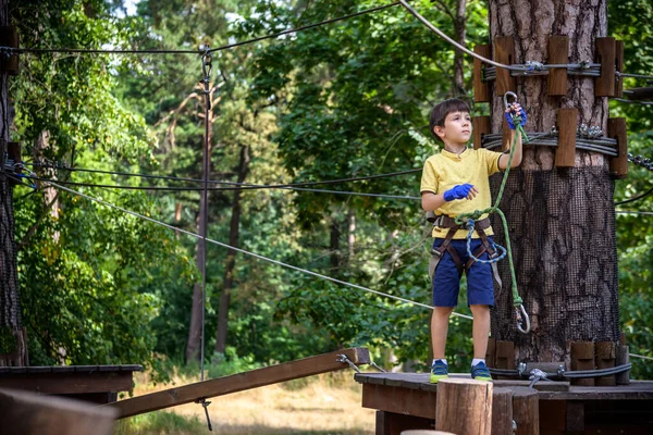 Halat parkında oynayan heyecanlı genç çocuk. Güneşli bir günde günlük giysiler ve spor ayakkabılar giyen beyaz bir çocuk. Çocuk konseptiyle aktif boş zaman.