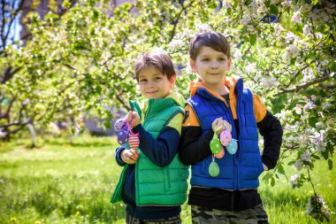 Başarılı yumurta avından sonra iki kardeş arkadaş ellerinde paskalya yumurtalarıyla ayakta ve gülümsüyorlar. Geleneksel Paskalya avı.