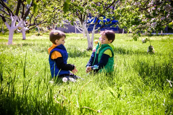 春の庭でイースターエッグハントの子供たち 花の牧草地でカラフルな卵を探している子供たち 幼児男の子と彼の兄友人子供男の子遊び屋外 — ストック写真