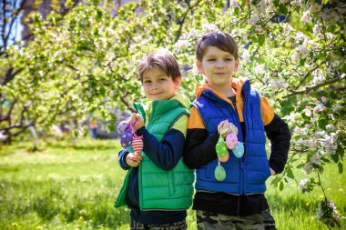 Başarılı yumurta avından sonra iki kardeş arkadaş ellerinde paskalya yumurtalarıyla ayakta ve gülümsüyorlar. Geleneksel Paskalya avı.