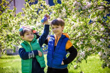Başarılı yumurta avından sonra iki kardeş arkadaş ellerinde paskalya yumurtalarıyla ayakta ve gülümsüyorlar. Geleneksel Paskalya avı.