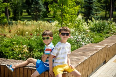 Gülümseyen çocukların şehir parkında vakit geçirmesi, çocuk ve kardeşinin bankta oturması... Mutlu çocukluk kavramı. Neşeli çocuklar doğada dinleniyor..