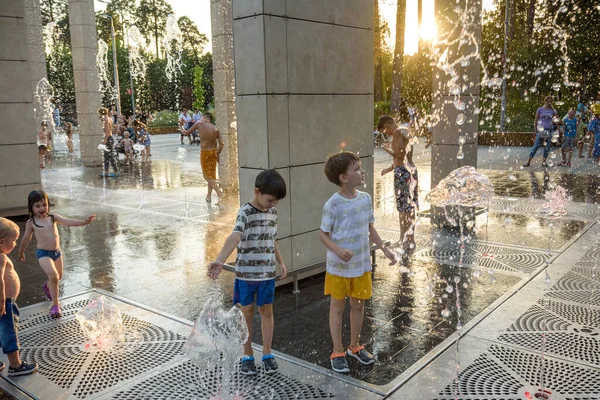 Kyiv, Ukrayna - 01 Ağustos 2021: Çeşmelere atlayan çocuklar. Çocuklar sıcak yaz gününde şehir çeşmesiyle oynuyorlar. Mutlu arkadaşlar çeşmede eğleniyor. Yaz havası. Arkadaşlık, yaşam tarzı ve tatil.