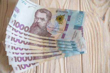Beyaz arka planda 1000 Ukrayna parası Hryvnia 'yı kapatın. Metin için fotokopi alanı olan bir iş alanı yatıyordu. Kriz ve mali çalkantı, enflasyon, devalüasyon, ekonomik depresyon sorunu.