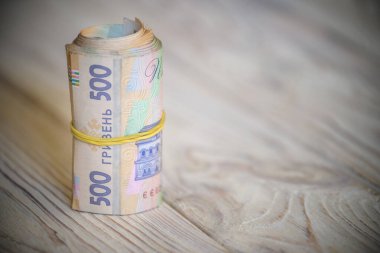 Yeni Ukrayna Hrivnia 'sı. 500 Hryvnia ahşap masa üzerinde lastik bantla tüpe bağlanmış. para geçmişi ve zenginlik kavramı.