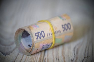 Yeni Ukrayna Hrivnia 'sı. 500 Hryvnia ahşap masa üzerinde lastik bantla tüpe bağlanmış. para geçmişi ve zenginlik kavramı.