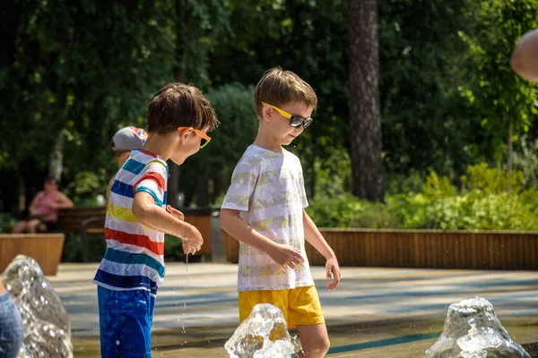 Boy having fun in water fountains. Child playing with a city fountain on hot summer day. Happy kids having fun in fountain. Summer weather. Active leisure, lifestyle and vacation.