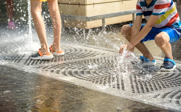 Boy having fun in water fountains. Child playing with a city fountain on hot summer day. Happy kids having fun in fountain. Summer weather. Active leisure, lifestyle and vacation.