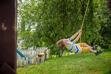 Mutlu küçük çocuk şehir dışında dinlenirken bulduğu bir salıncakta eğleniyor. Çocuklarla aktif boş zaman.