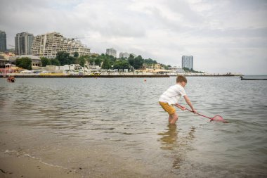 Küçük bir çocuk tek başına deniz kıyısına doğru yürüyen dalgalarla kumsalı keşfediyor. Mutlu çocukluk kavramı.