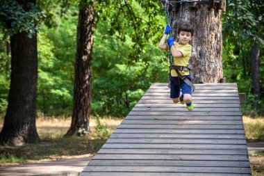 Halat parkında oynayan heyecanlı genç çocuk. Güneşli bir günde günlük giysiler ve spor ayakkabılar giyen beyaz bir çocuk. Çocuk konseptiyle aktif boş zaman.
