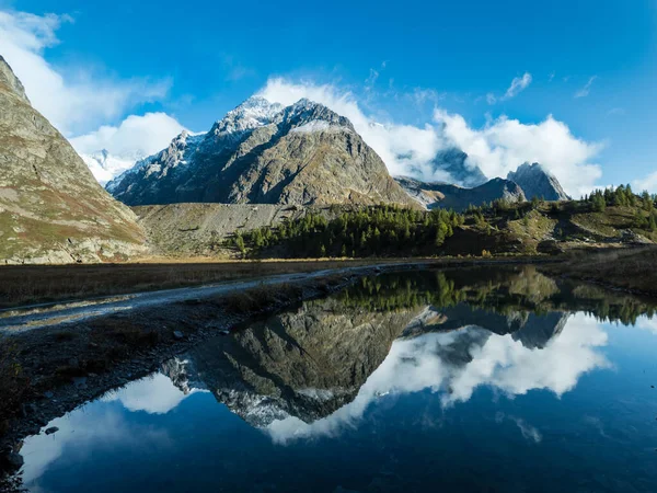 Dağ zirvesi. Dağ manzarası. Dağlarda yaz. Dağ nehri. Dağ vadisi. Dağlardaki göl. Sudaki dağların yansıması.