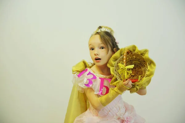 Una ragazza in un elegante abito da ballo con l'alfabeto e un cesto d'oro tra le mani su uno sfondo bianco — Foto Stock