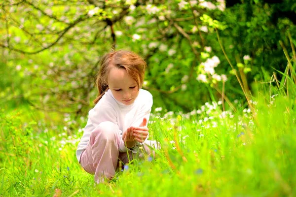 En flicka i krans av blommor på en grön äng i en vit jacka på våren och sommaren — Stockfoto