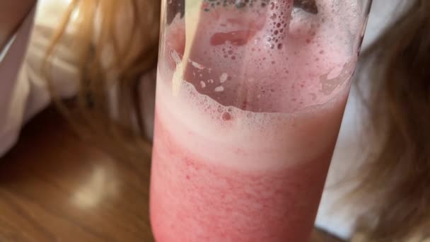 Una chica bebe un cóctel rosa de una pajita roja en un restaurante — Vídeos de Stock