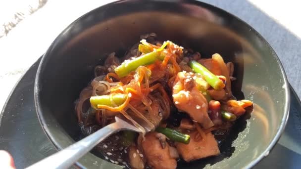 Hot Funchose s mořskou zeleninou a masem v černém talíři zblízka — Stock video