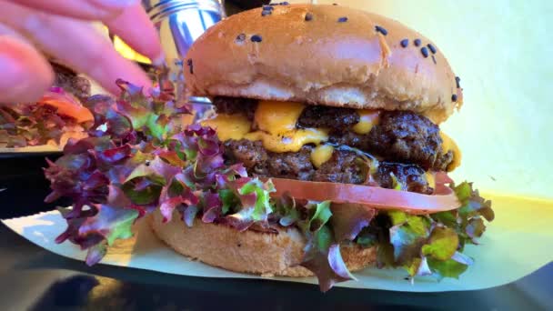 Hambúrguer suculento filmagem hambúrguer com folhas de alface close-up com molho delicioso — Vídeo de Stock