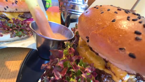 Hamburguesa jugosa con hojas de lechuga en primer plano con deliciosa salsa — Vídeos de Stock