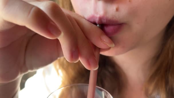 Una chica bebe un cóctel rosa de una pajita roja en un restaurante — Vídeos de Stock