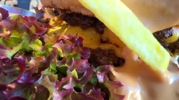 Hamburguesa jugosa con hojas de lechuga en primer plano con deliciosa salsa — Vídeos de Stock