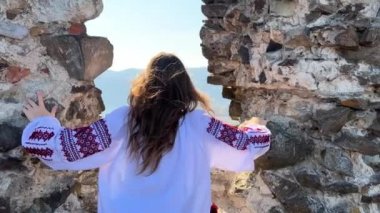 Savaş yok Ukraynalı genç kız eski bir şatonun harabelerinde nakışlı bir bluz içinde ne yazık ki ve etrafındaki her şeye bakıyor.