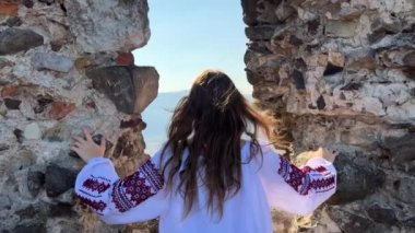 Savaş yok Ukraynalı genç kız eski bir şatonun harabelerinde nakışlı bir bluz içinde ne yazık ki ve etrafındaki her şeye bakıyor.