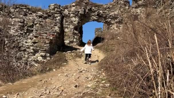 Ninguna joven ucraniana de guerra en una blusa bordada en las ruinas de un viejo castillo tristemente y mira todo a su alrededor — Vídeo de stock