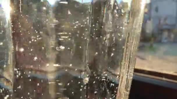Acqua gassata nel vetro sullo sfondo della finestra e il sole nel vetro molte bolle d'aria sorgono — Video Stock