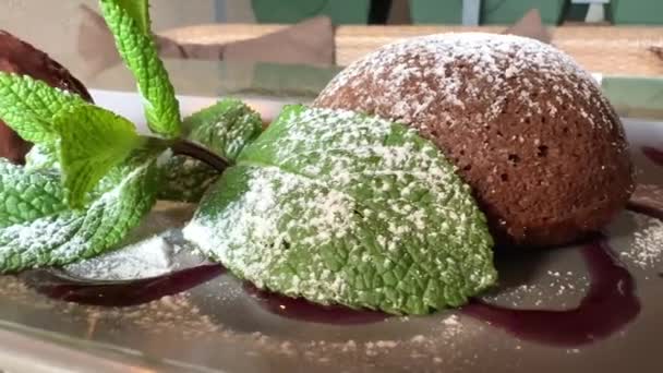 Fondant con chocolate caliente y menta al lado de helado marrón frío apetitoso y delicioso postre — Vídeo de stock