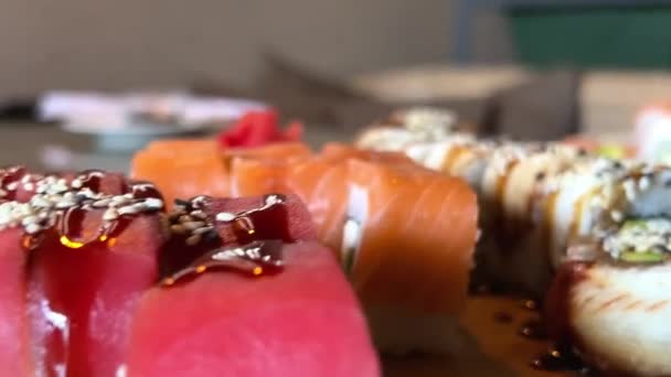 Ställ sushi philadelphia med lossos tonfisk och ål på en träskiva i restaurangen äta med ätpinnar det är mycket välsmakande och trevlig — Stockvideo