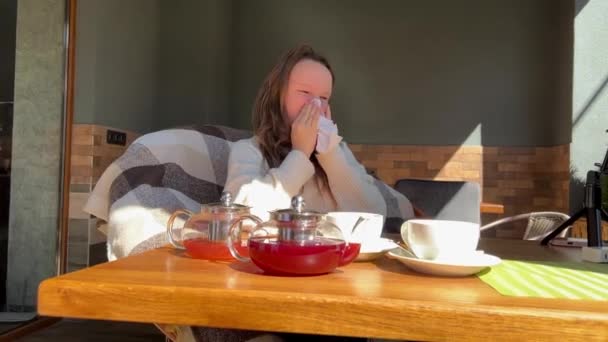 Alergia estacional chica adolescente sopla su nariz en una mesa cerca de té alergénico en la primavera — Vídeo de stock