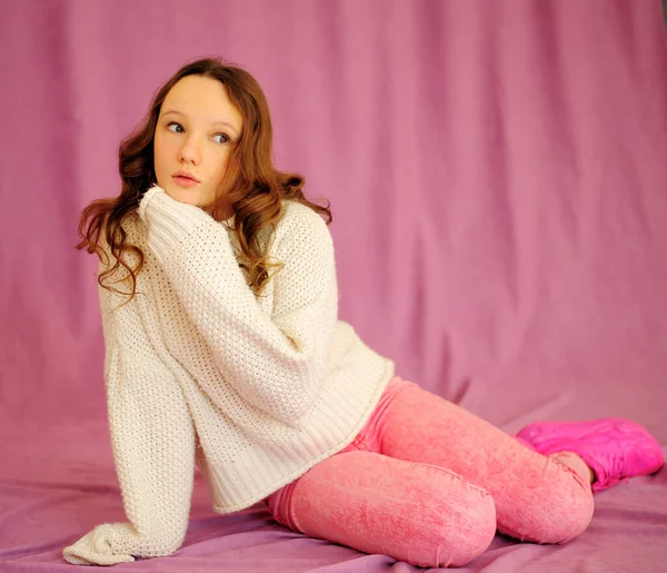 Uma jovem caucasiana em um fundo rosa em roupas rosa e branca senta-se com emoções e gentilmente olha ao redor há um lugar para o texto — Fotografia de Stock