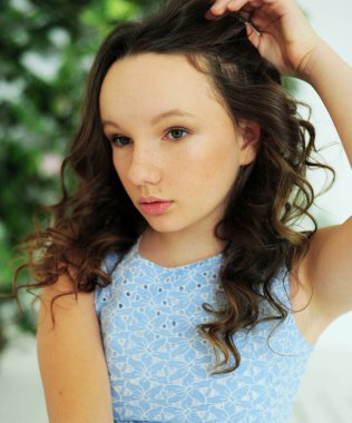 Stüdyodaki mavi elbiseli kız. Kahverengi saçlı ve beyaz tenli.