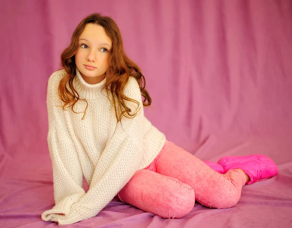 Uma jovem caucasiana em um fundo rosa em roupas rosa e branca senta-se com emoções e gentilmente olha ao redor há um lugar para o texto — Fotografia de Stock