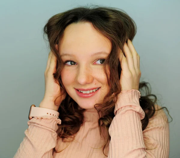 Una chica en un estudio de maquillaje tinager en rosa sonrisas de golf feliz con un nuevo maquillaje en sus ojos refleja una lámpara para la fotografía suavemente pintadas pestañas y labios pelo chica rubia 10-13 años — Foto de Stock