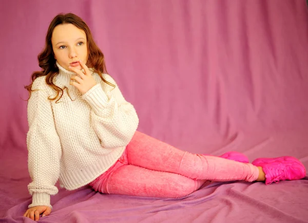 Una giovane ragazza caucasica su uno sfondo rosa in abiti rosa e bianchi si siede con emozioni e delicatamente si guarda intorno c'è un posto per il testo — Foto Stock