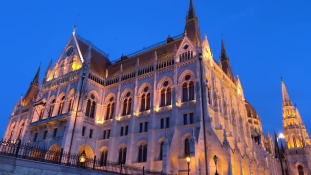 Palazzo del Parlamento ungherese a Budapest fotografia notturna di pareti luminose gialle e cielo blu scuro vicino al fiume Danubio 03.04.22 Budapest, Ungheria — Video Stock