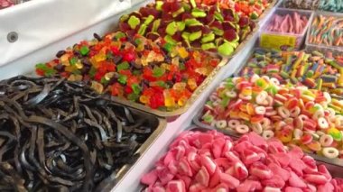 Tezgahtaki farklı tatlılar, gökkuşağının tüm renkleri, jöleli heykelcikten makarna ve çikolataya aktığı kadar serilmiştir..